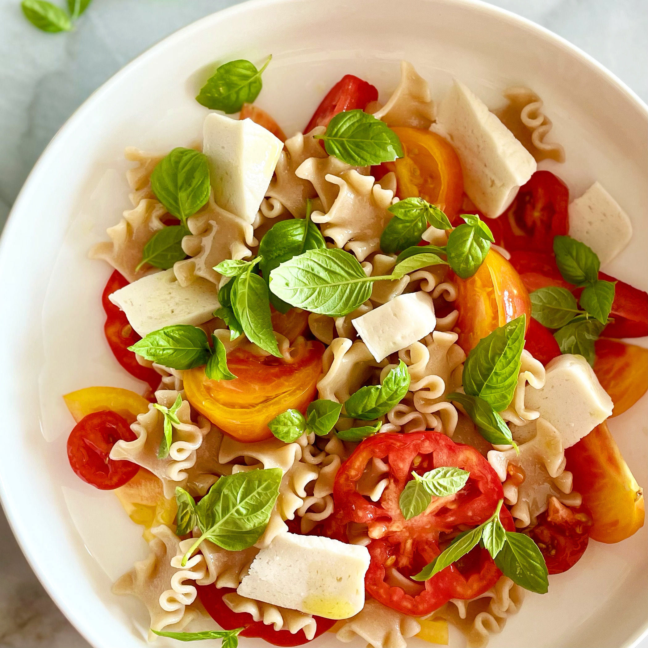 pasta with heirloom tomatoes, plant-based mozzarella, and basil