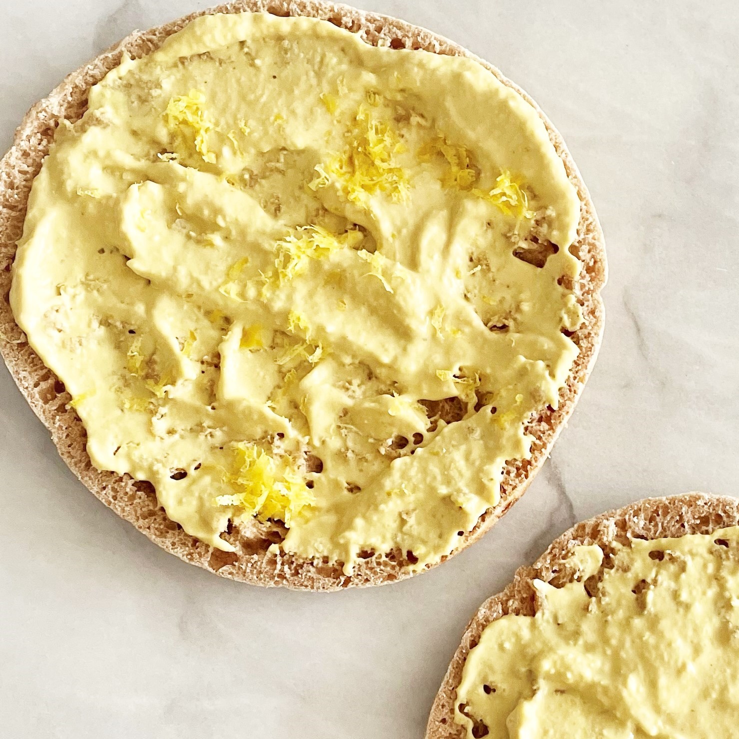 Pita round topped with roasted yellow pepper hummus
