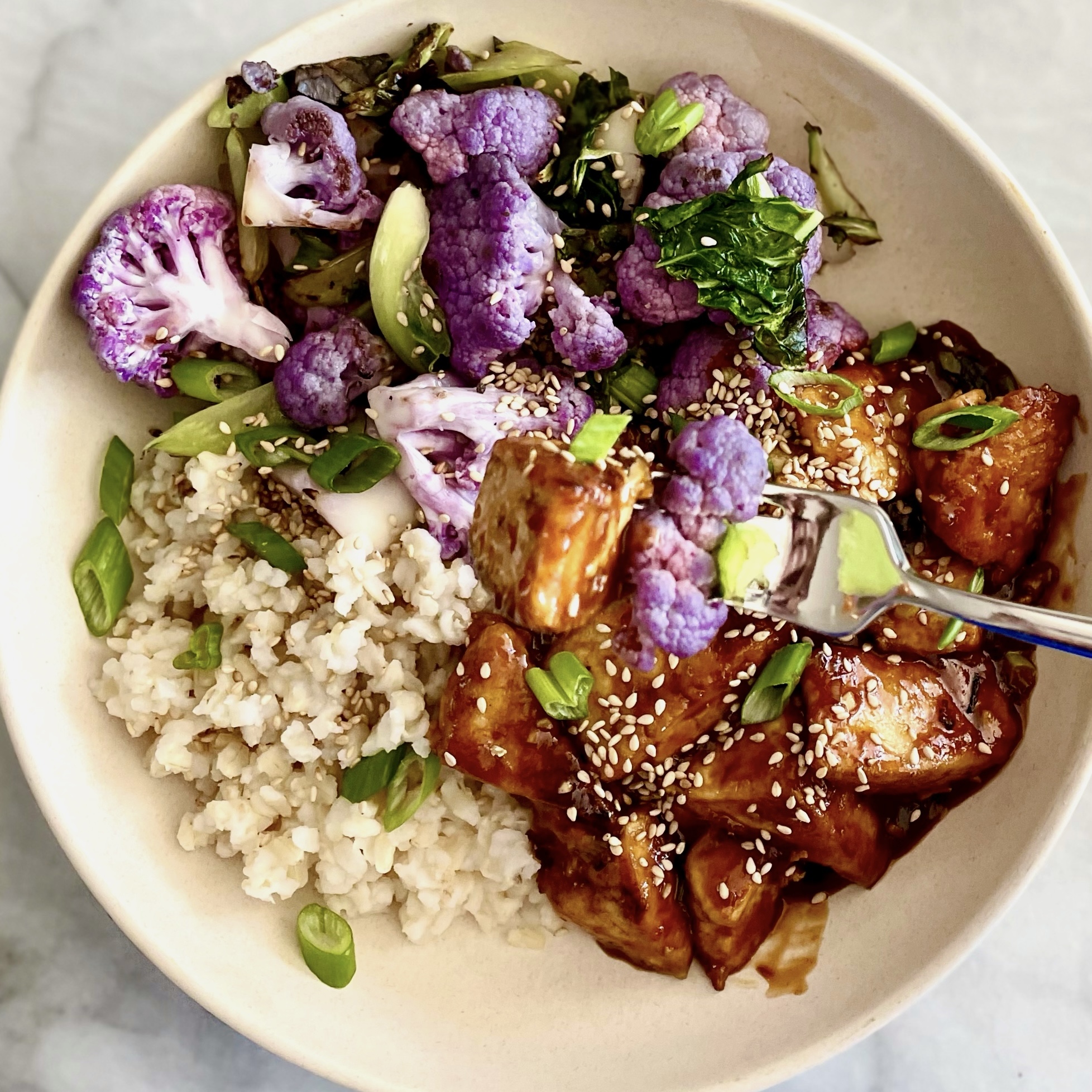 general tso’s tofu with cauliflower _in bowl with fork