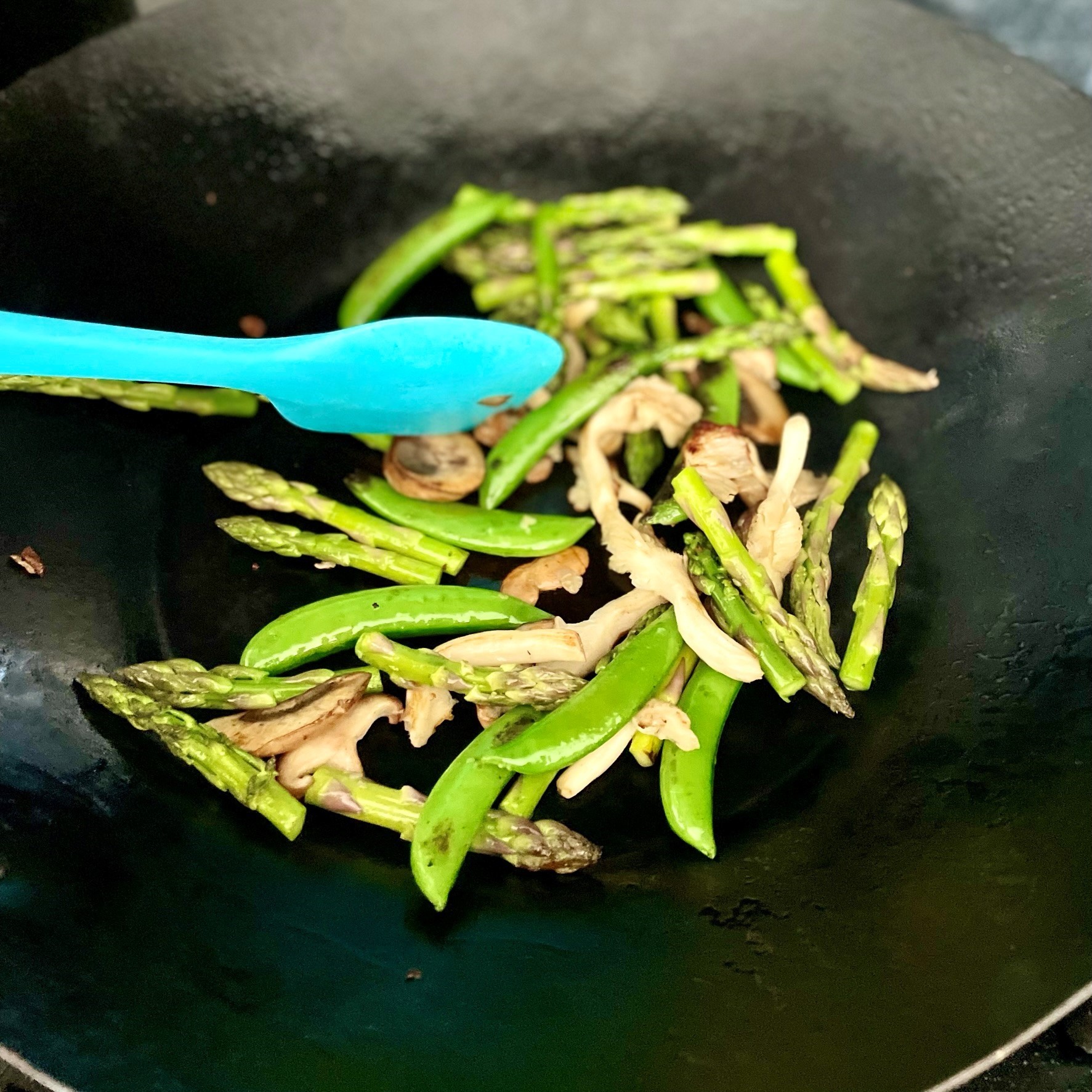 stir-frying seasonable vegetables for spring green flatbread with edamame pesto