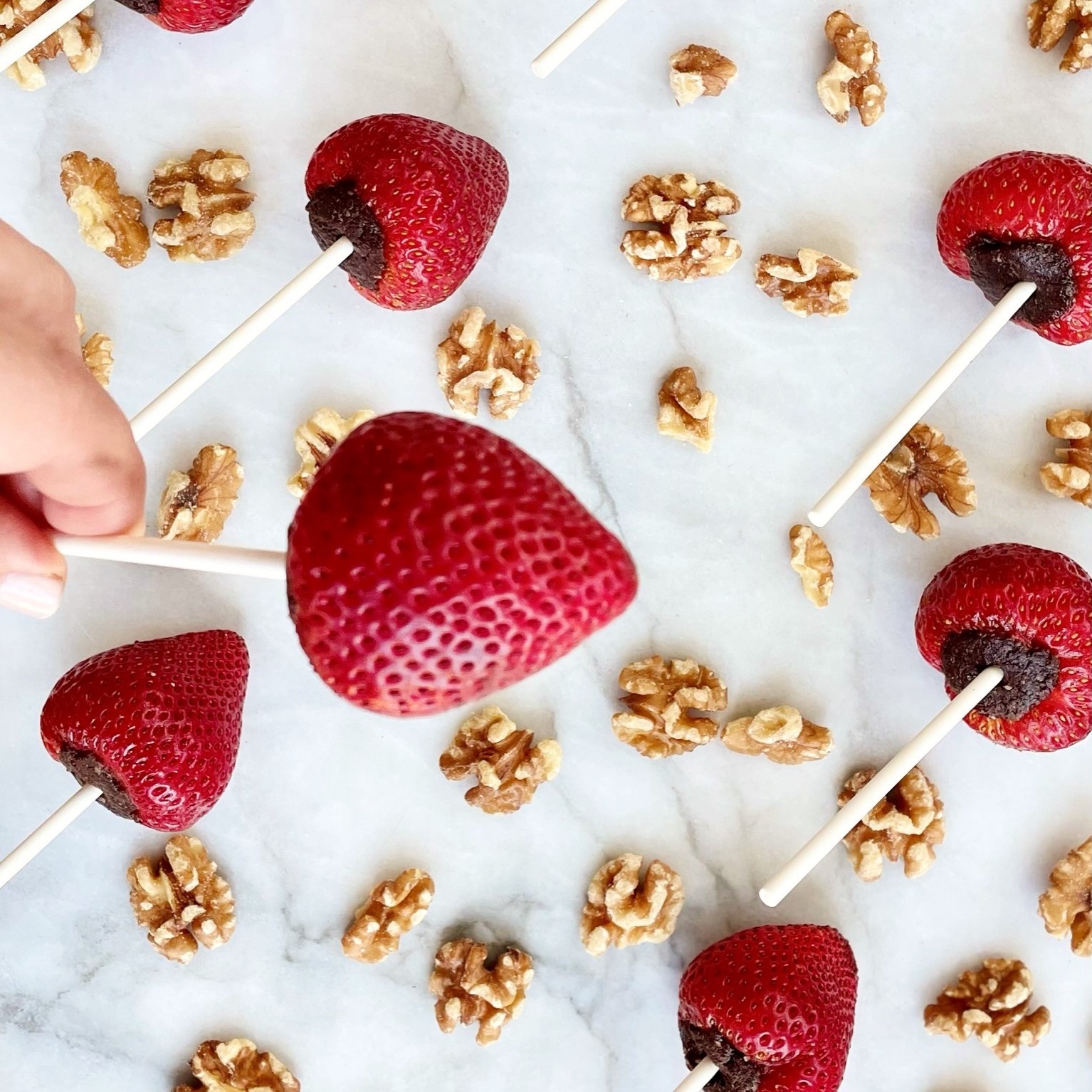 strawberry-walnut lollipops in background and holding one closeup