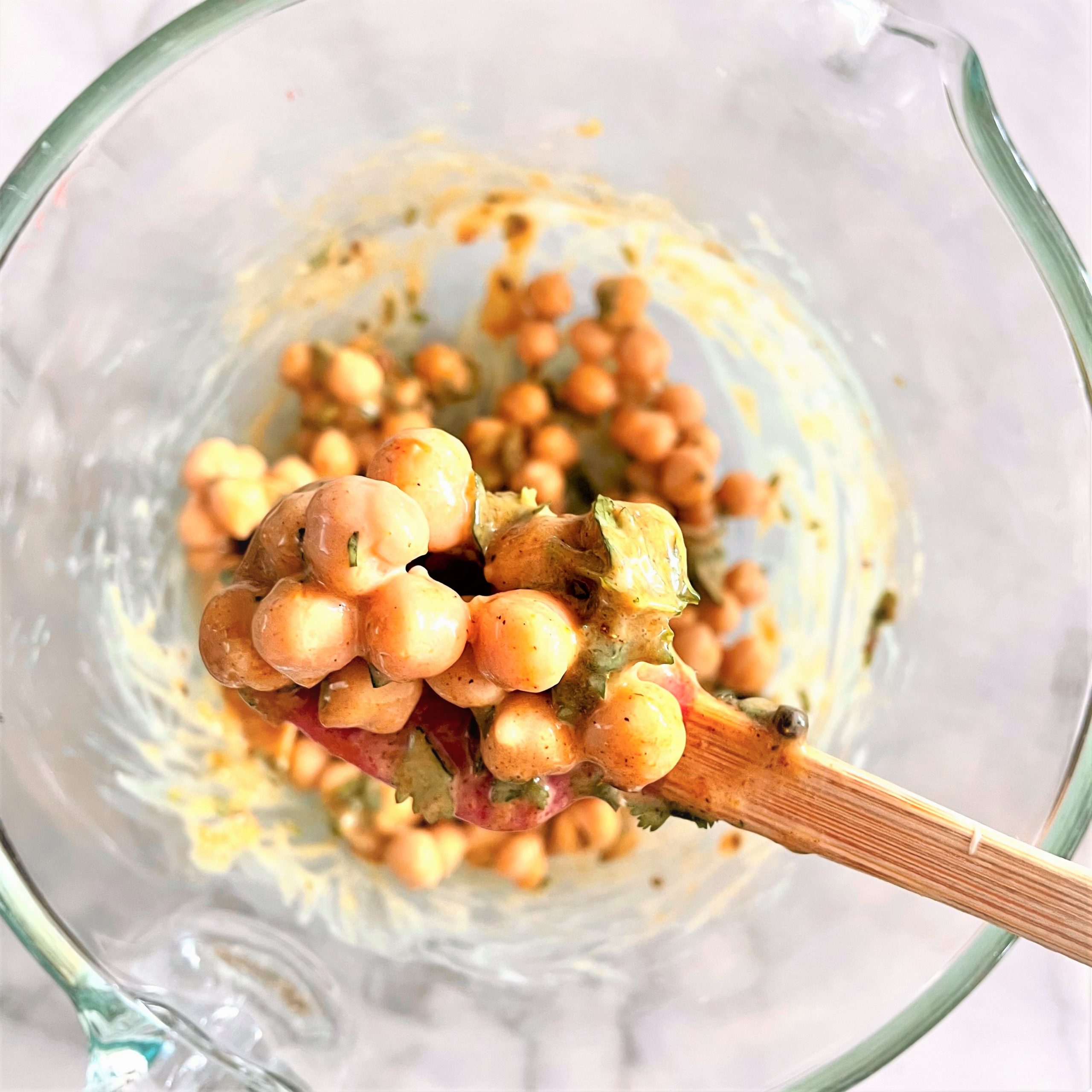 stirring curried chickpea salad with grilled veggies in a glass bowl