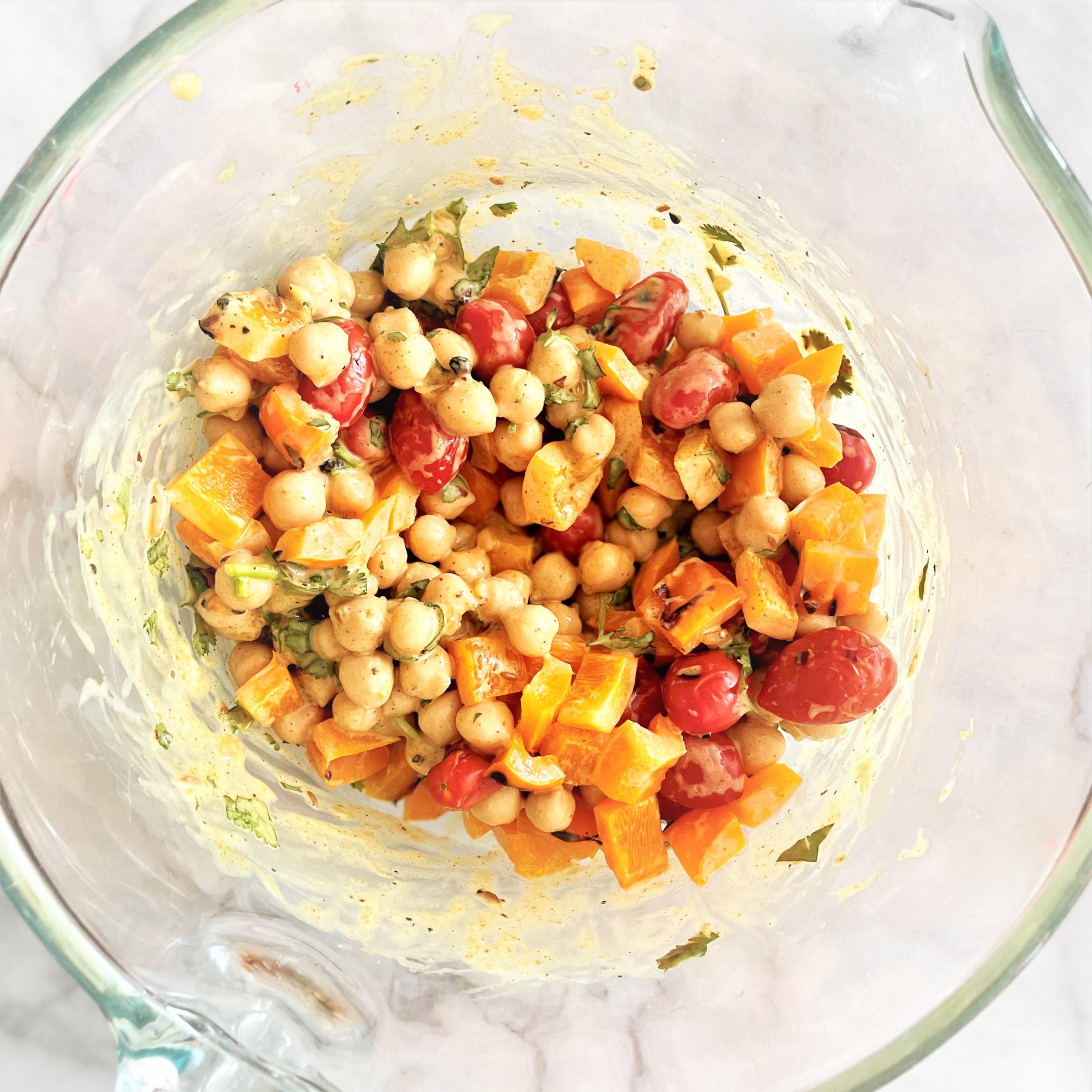 curried chickpea salad with grilled veggies in a glass mixing bowl
