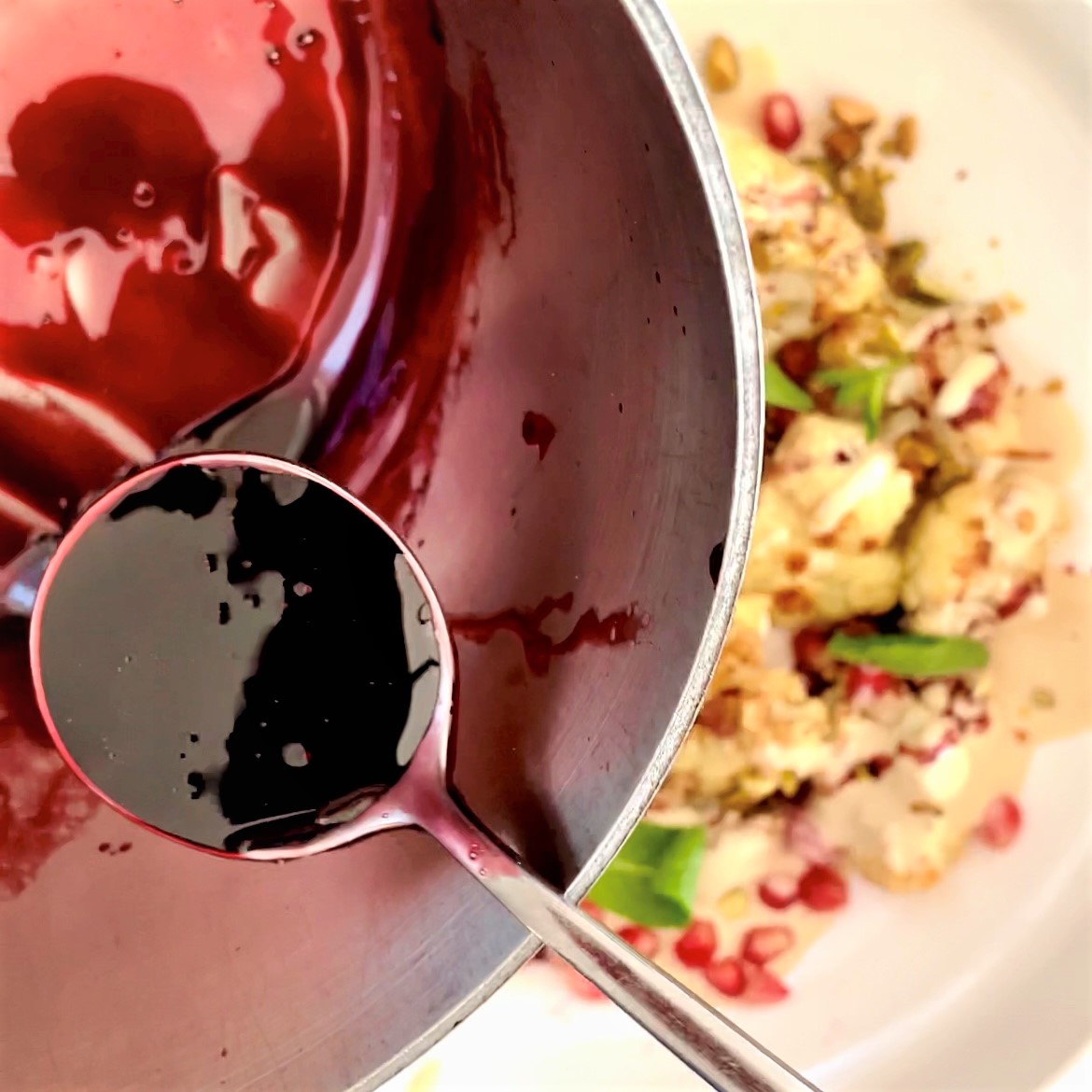 pomegranate reduction sauce in saucepan with a spoon