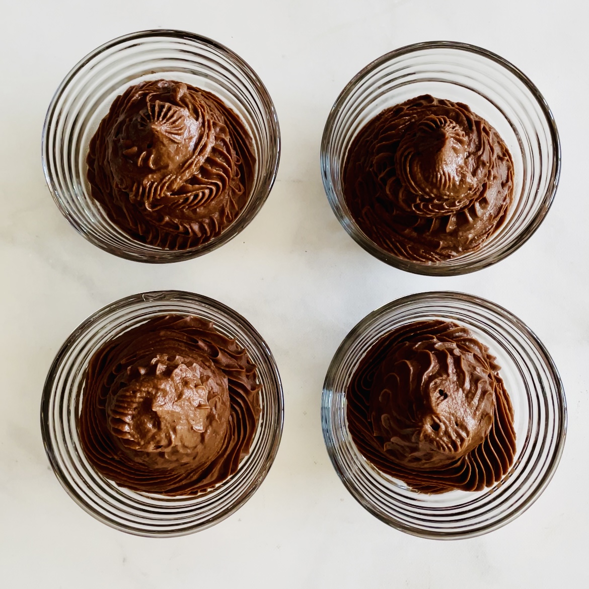 four glass bowls of no-cook plant-based cocoa mousse
