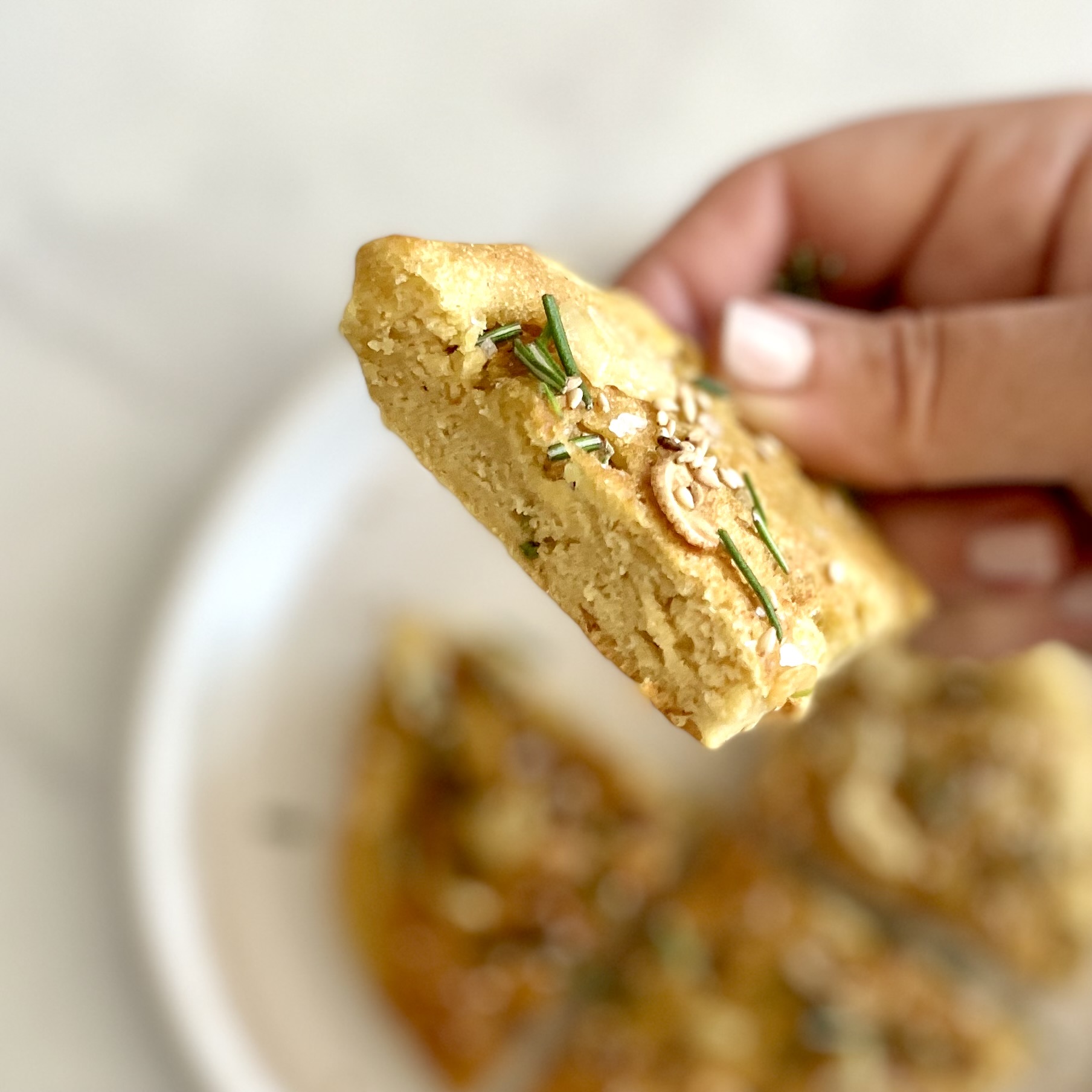 holding a wedge of focaccia-style skillet chickpea flatbread
