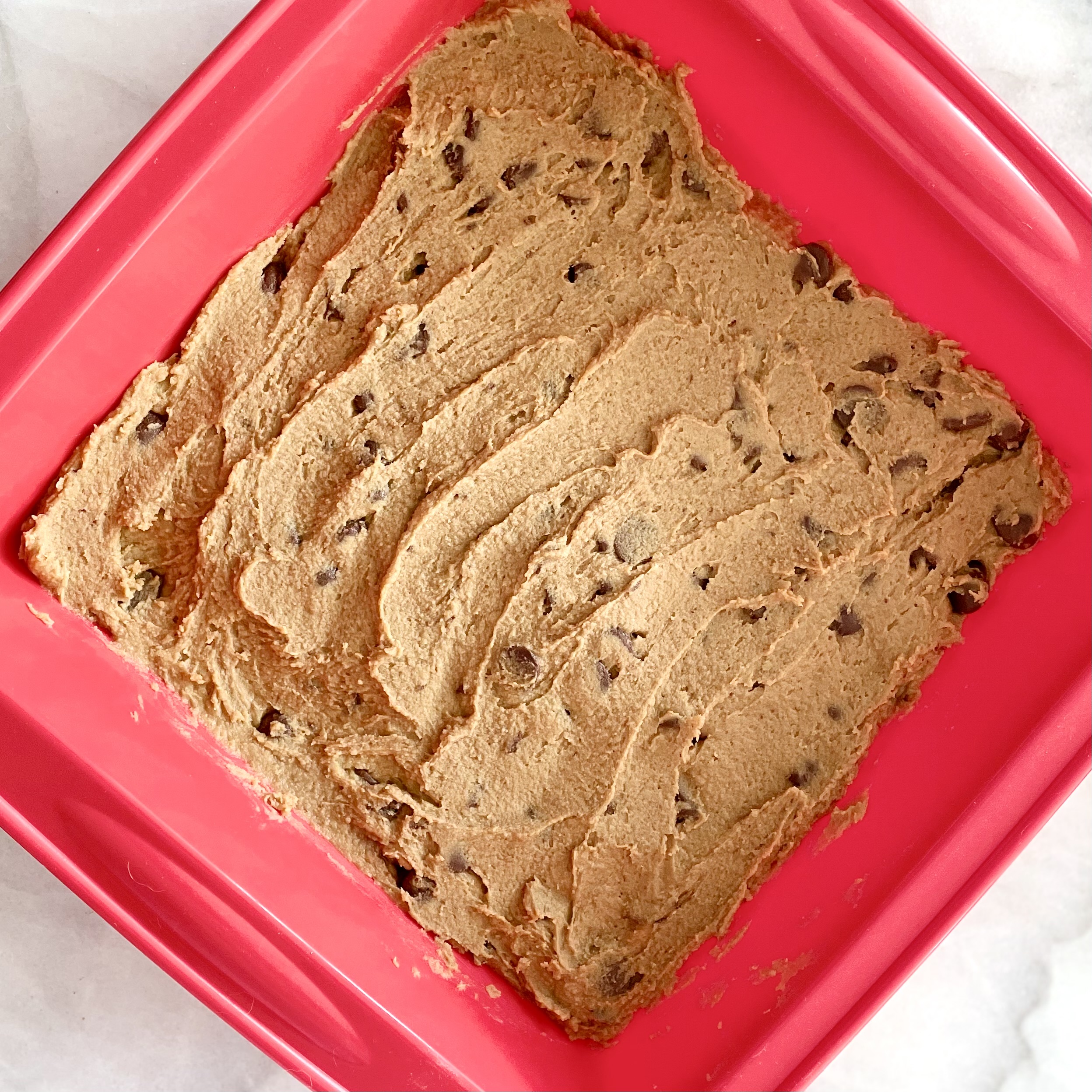 frozen chocolate chip-chickpea cookie dough snack bars in red silicone baking pan