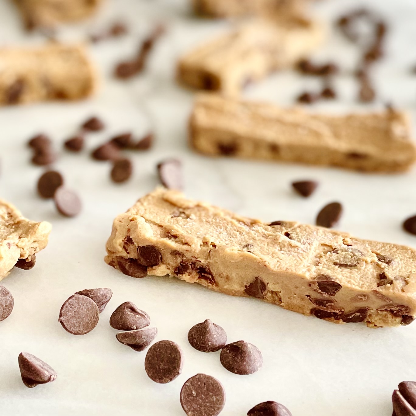 frozen chocolate chip-chickpea cookie dough snack bars on white marble with chocolate chips