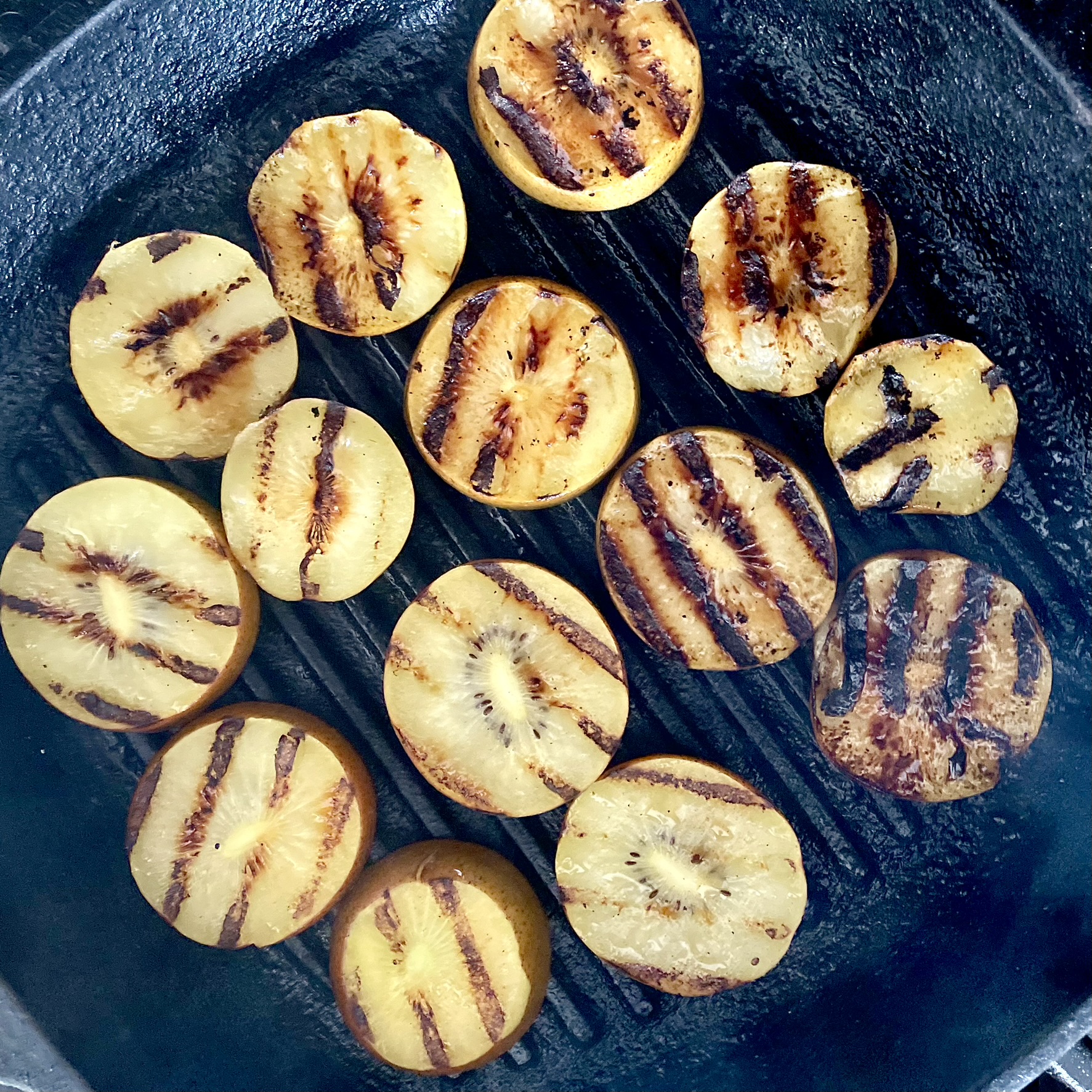pan-grilled golden kiwi slices on grill pan for grilled golden kiwi, strawberry and arugula salad