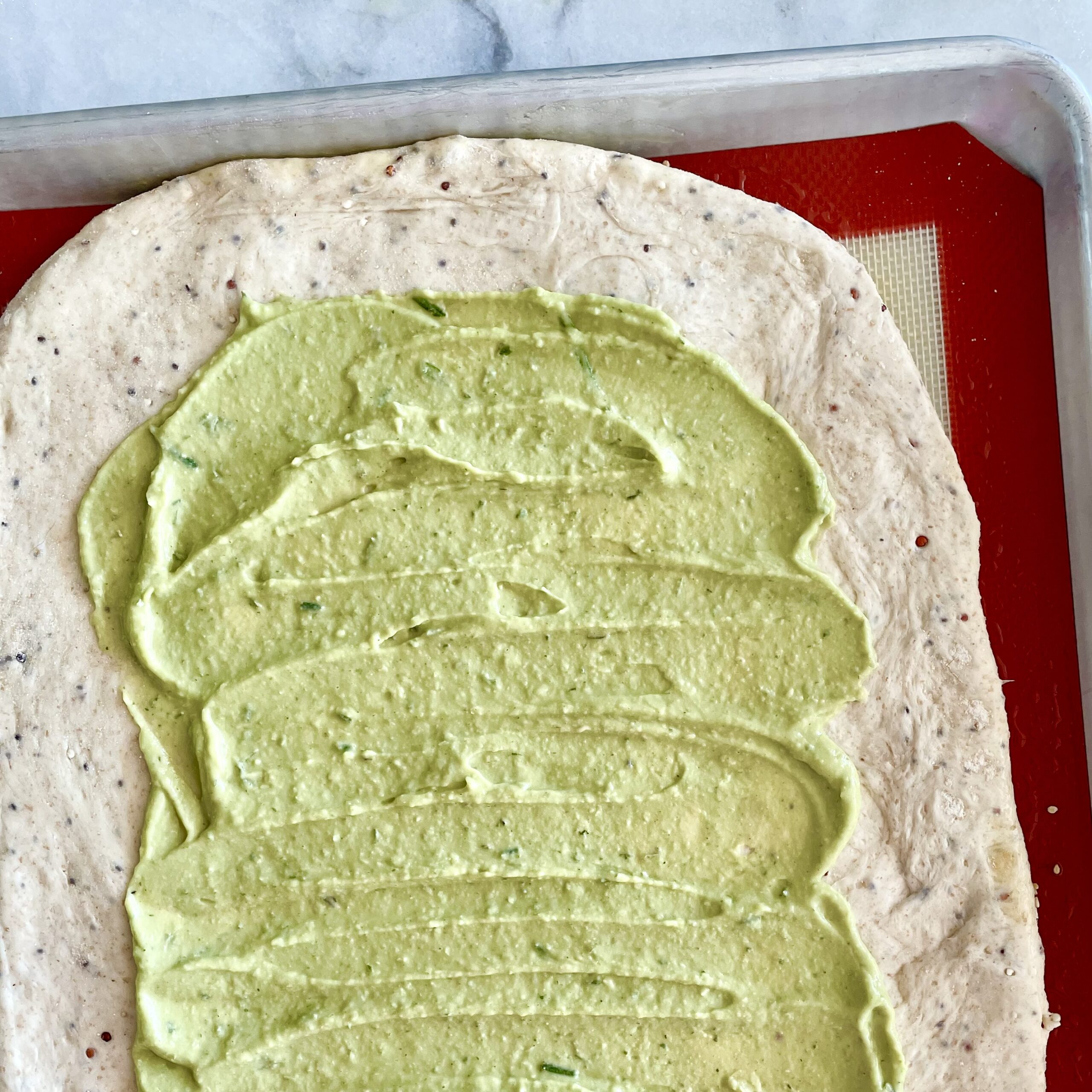 herbed white bean spread on dough for jerusalem bagel-style cherry tomato galette