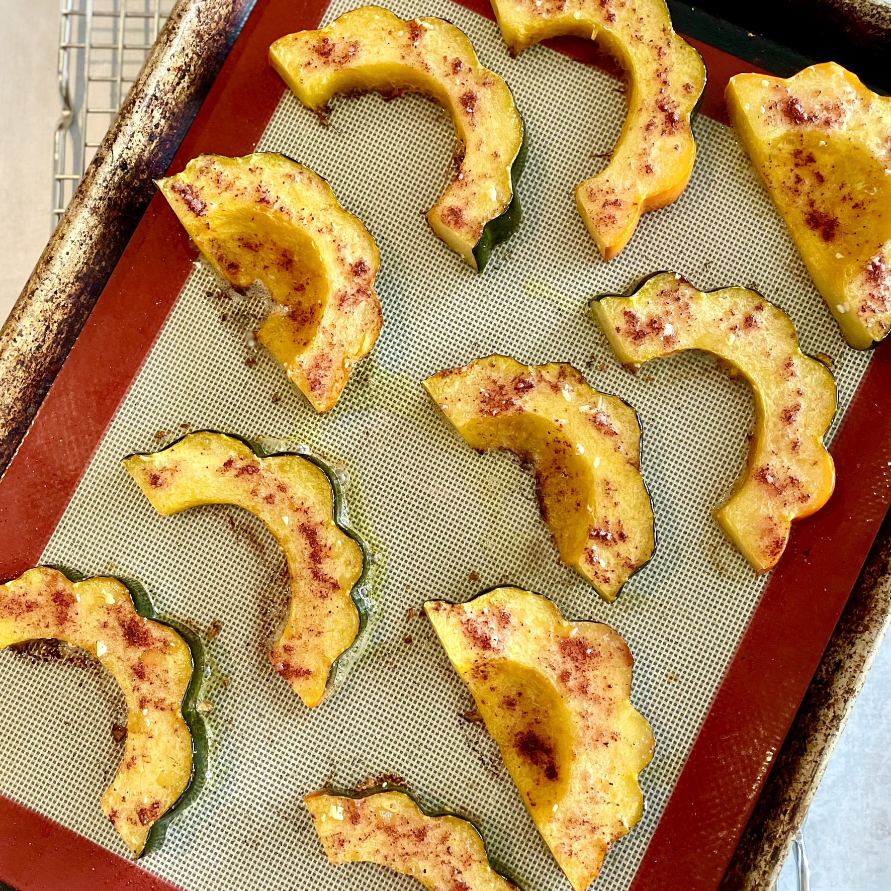 seasoned roasted acorn squash slices on a Silpat-lined baking sheet