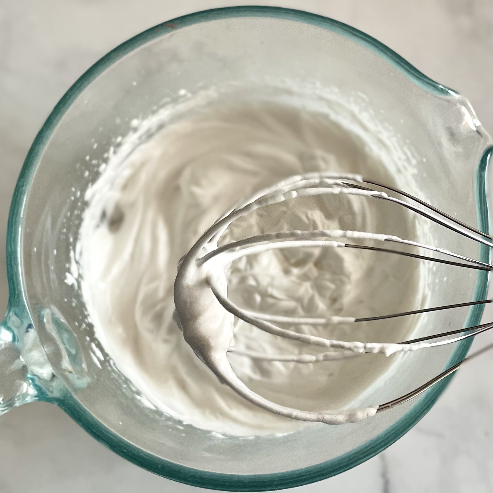 vanilla aquafaba whipped cream in a bowl with whisk beater attachment