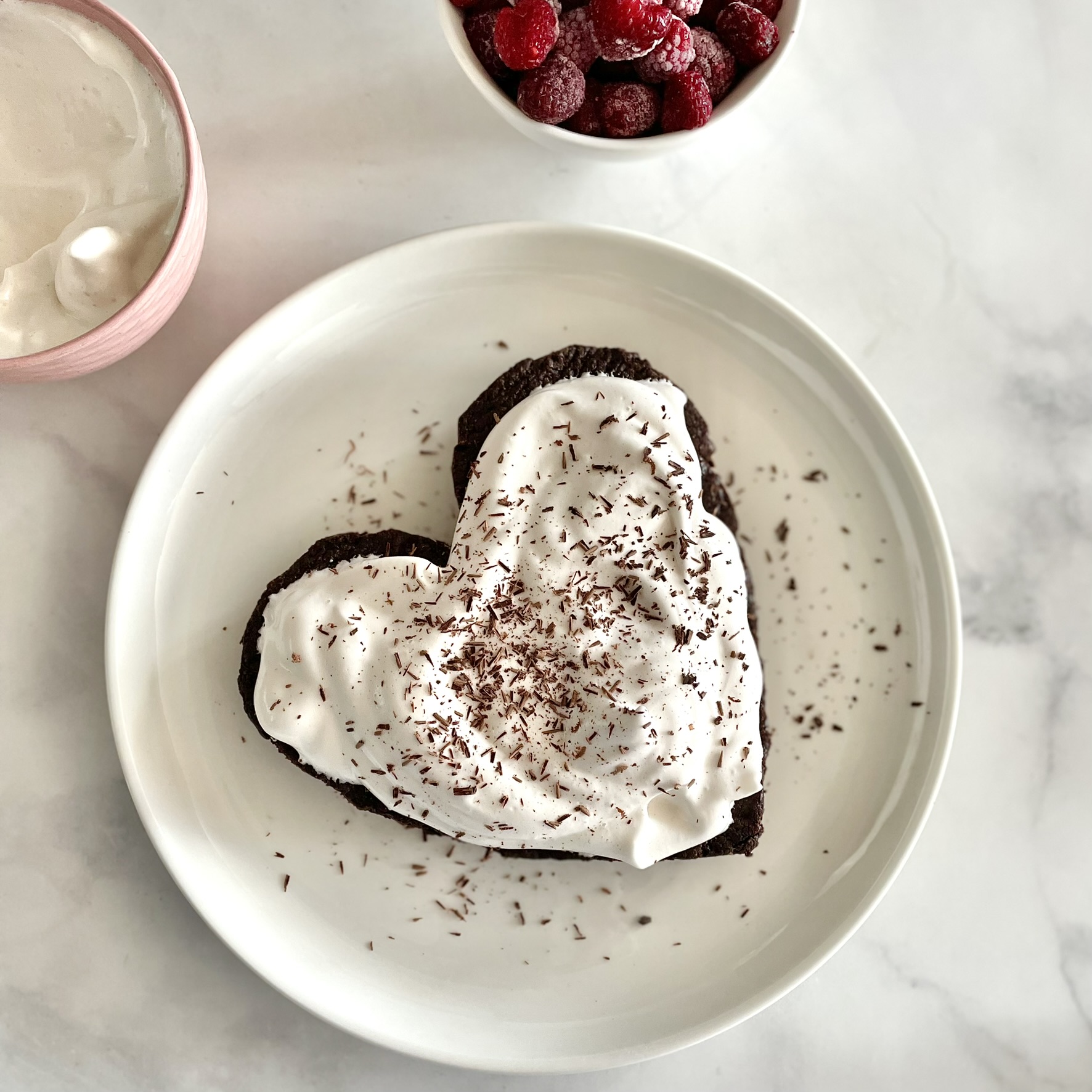 vanilla aquafaba whipped cream on a heart shaped brownie