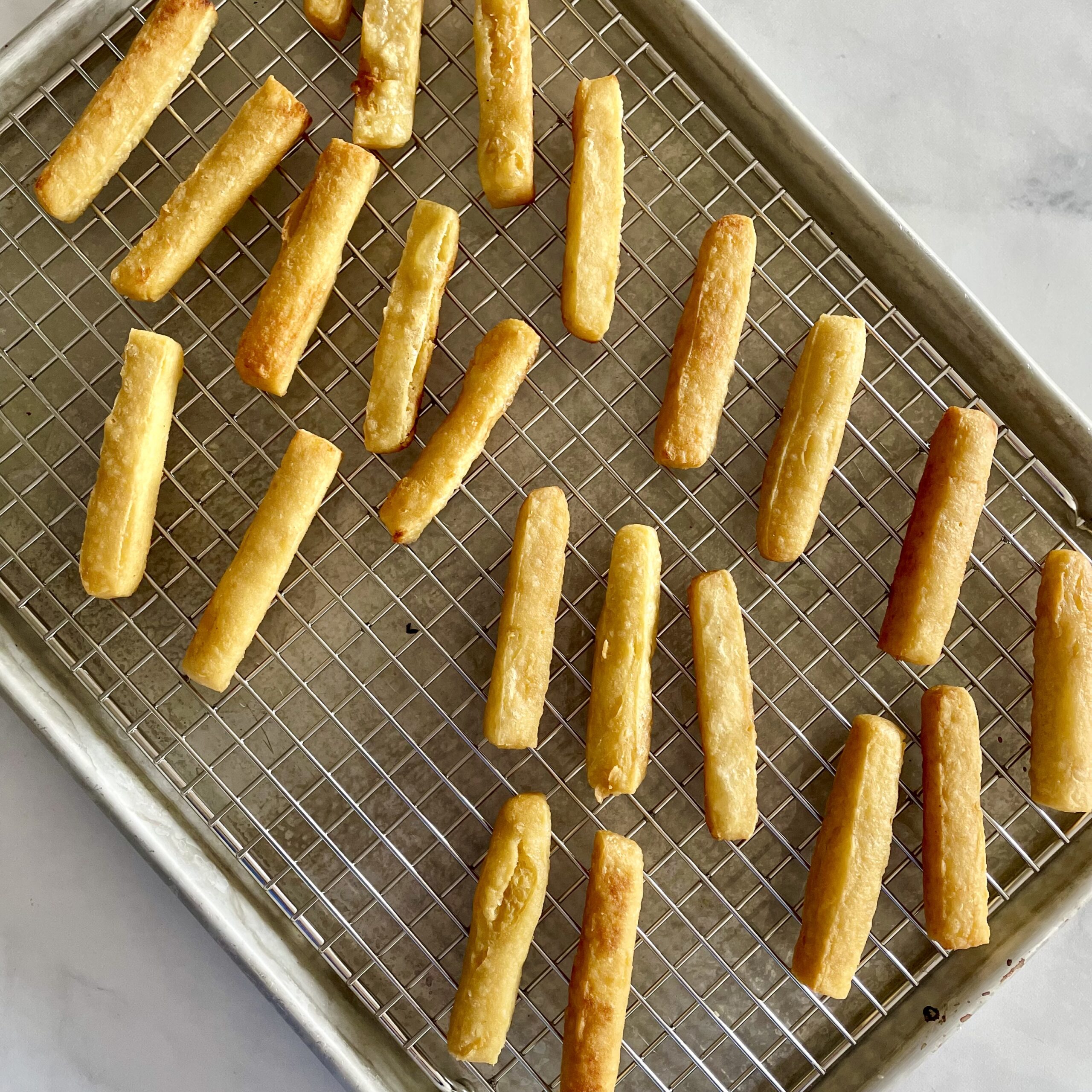 chickpea fries draining on wire rack set on a baking pan on marble surface
