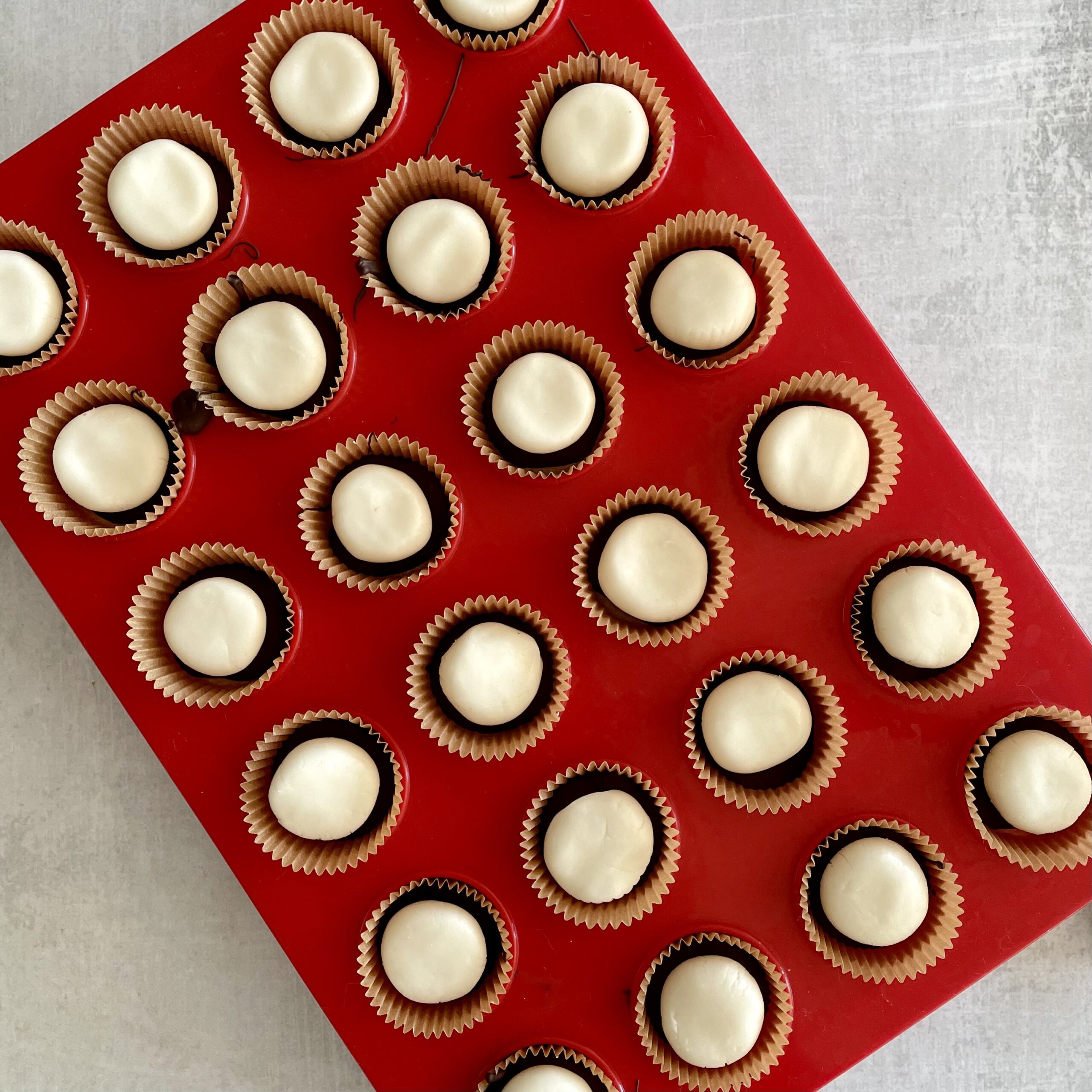 red muffin tray filling with white cream candies