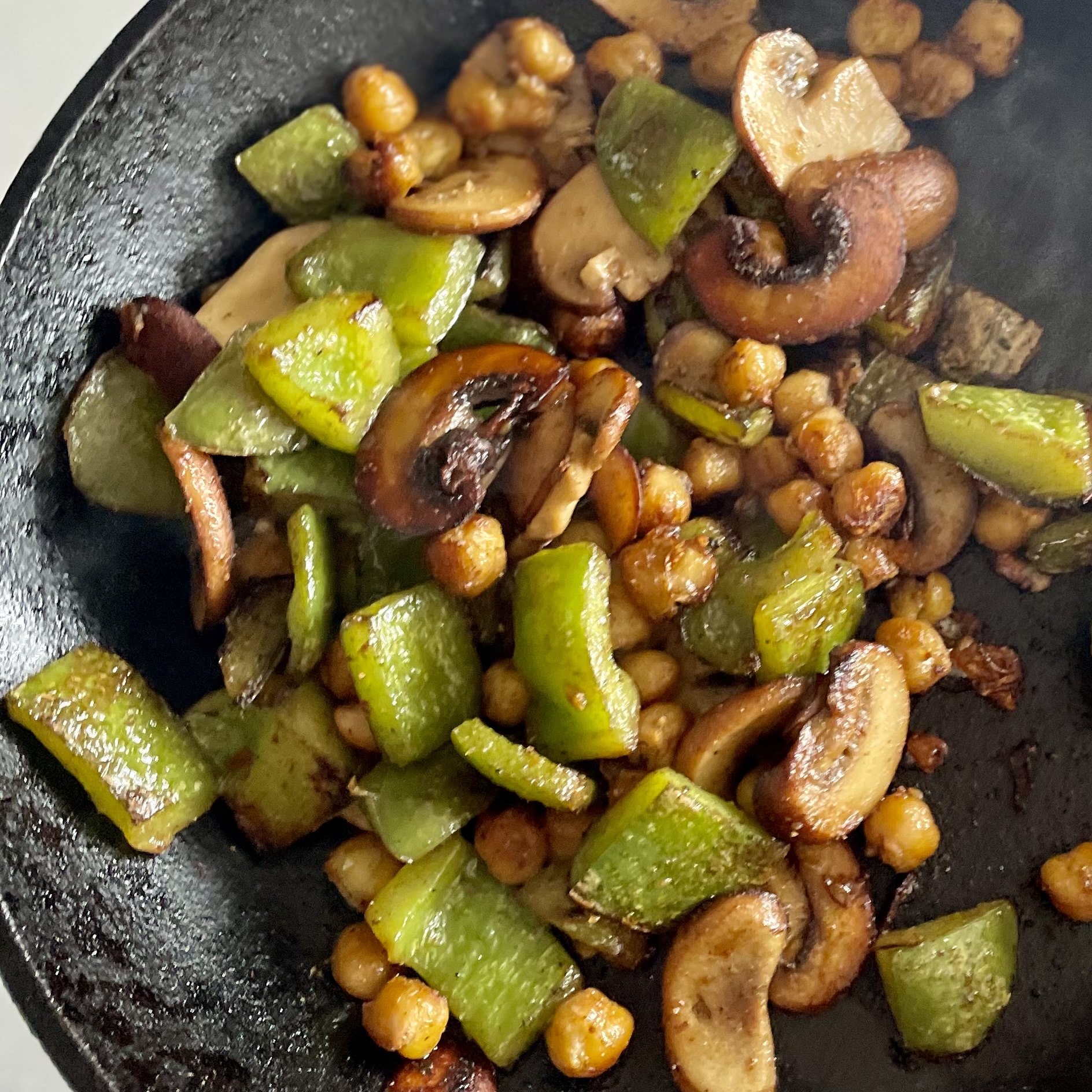 cast iron skillet with caramelized green bell pepper, cremini mushrooms, and chickpeas