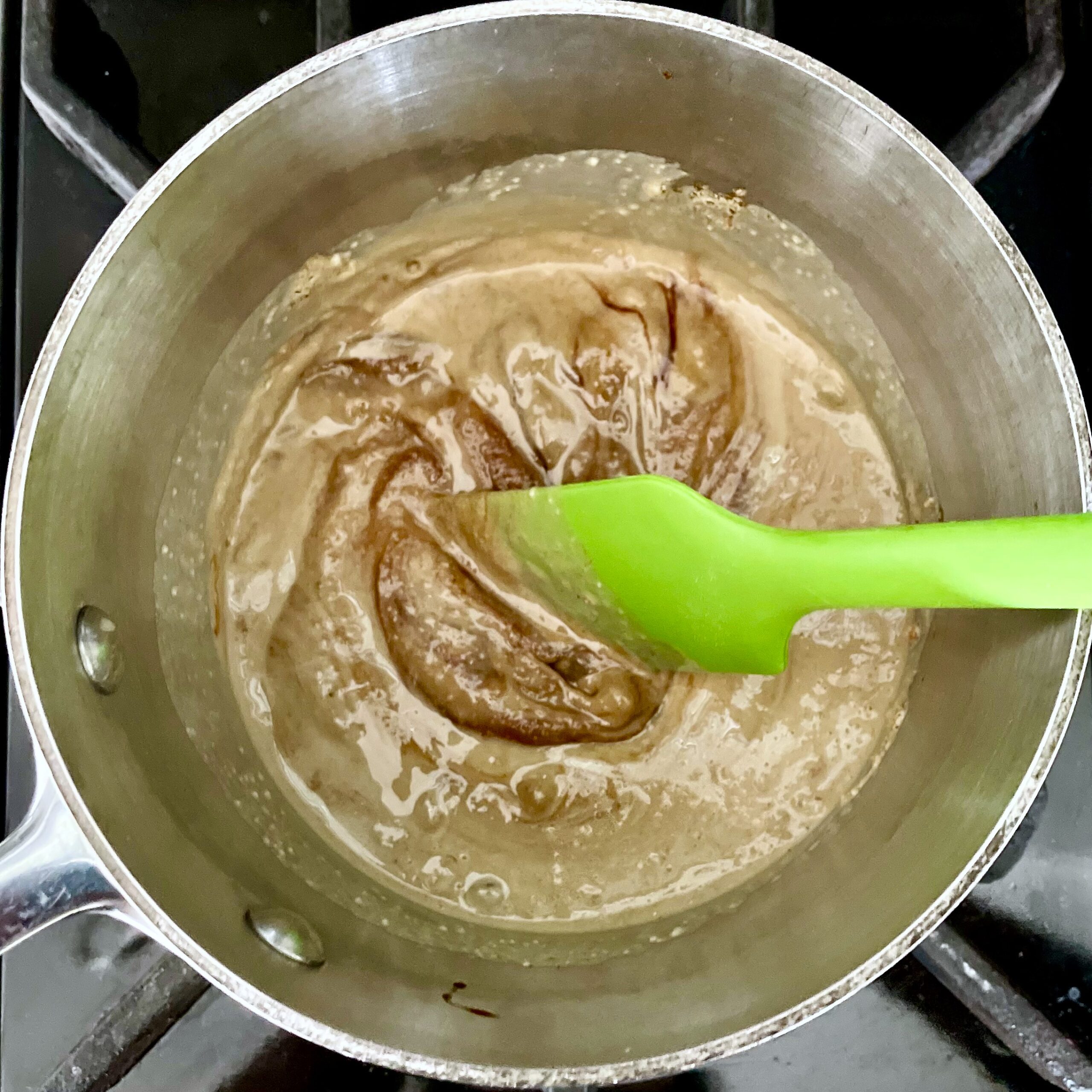 Stirring chocolate tahini fudge with sea salt on stove