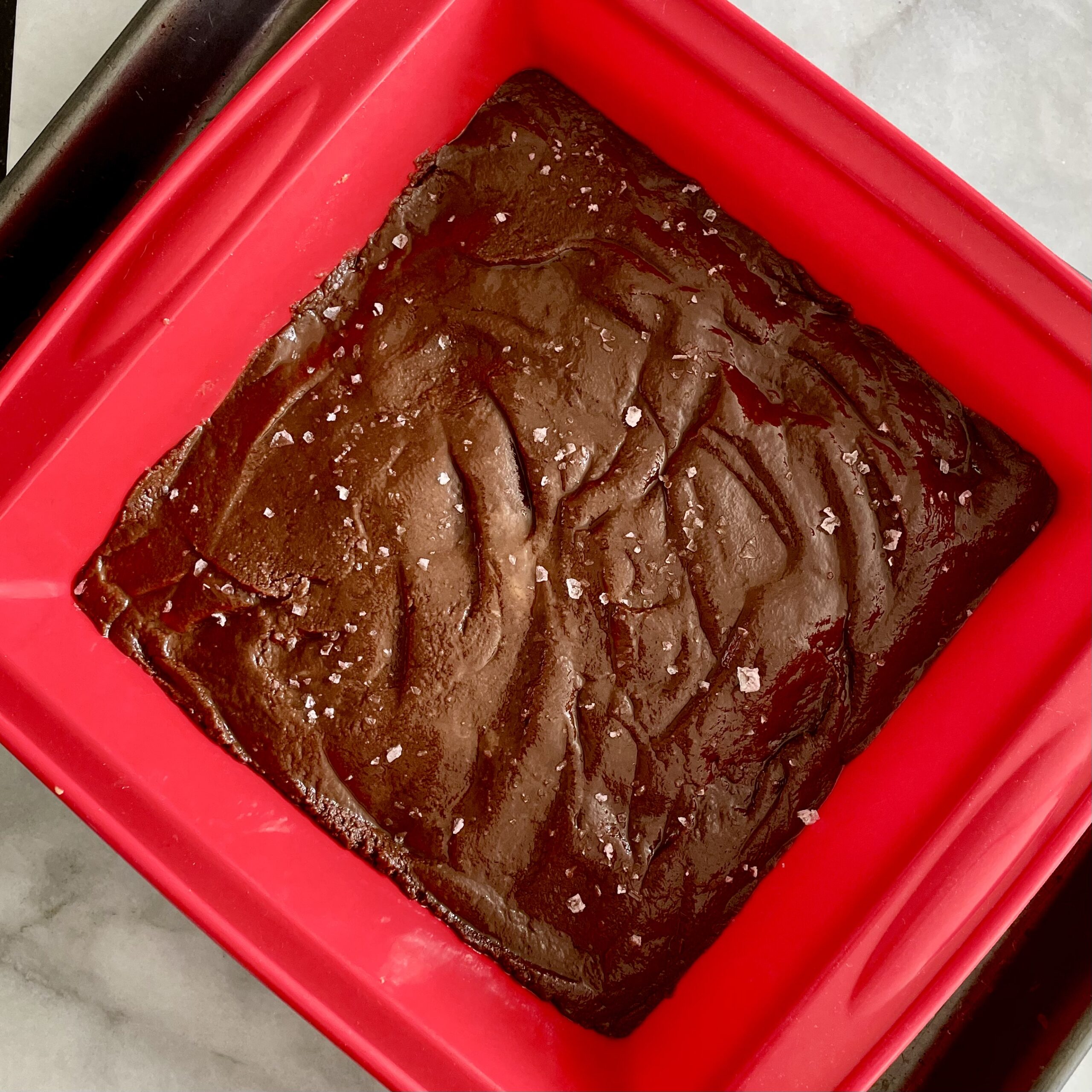 chocolate tahini fudge with sea salt spread into an 8-inch red silicone baking pan
