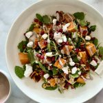 roasted sweet potato salad with pomegranate arils with small bowl of dressing on the side