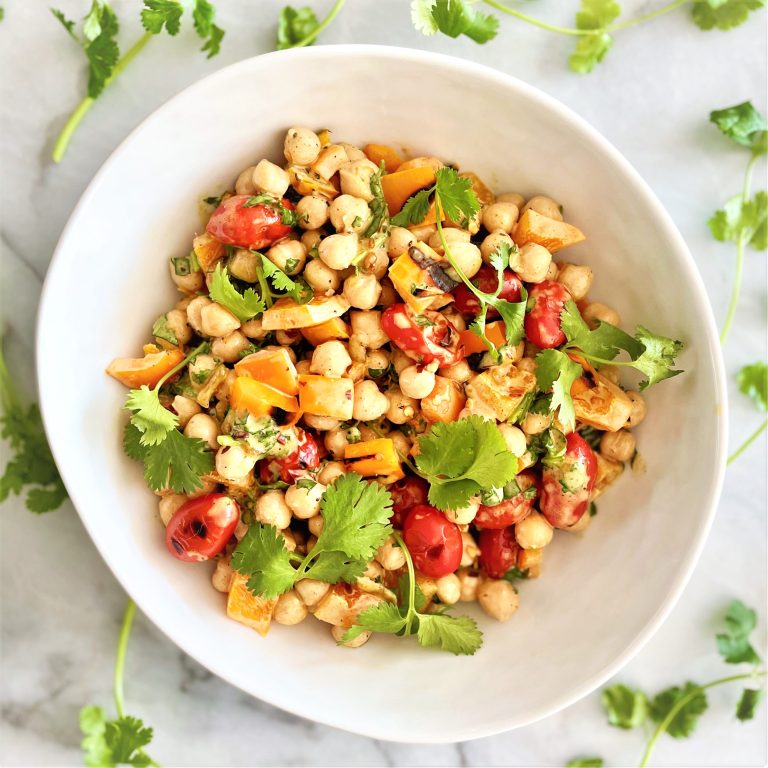 curried chickpea salad with grilled veggies om white bowl with cilantro garnish
